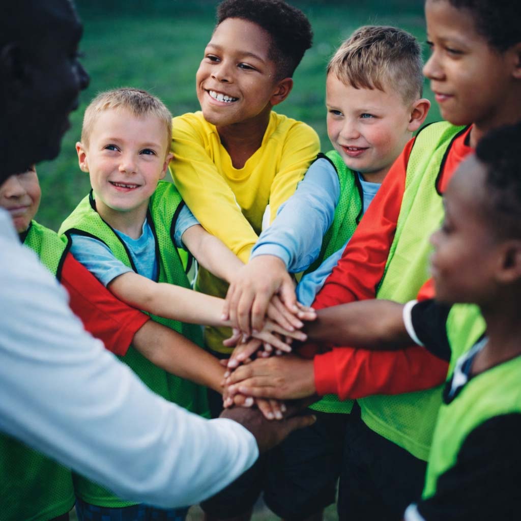 Kinder in Sporttrikots mit Teamgeist-Geste – Tippspiel für Charity und Spenden-Aktionen mit tippevent